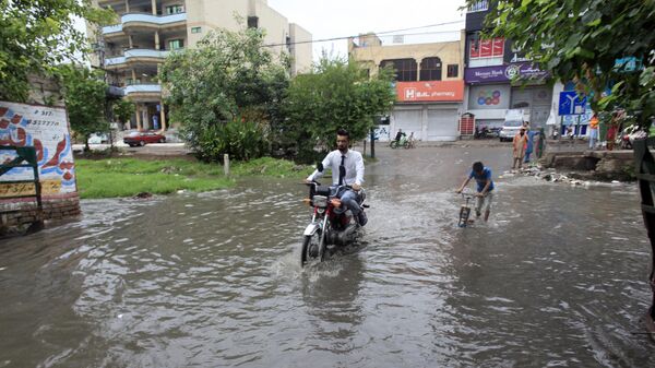 A motorcyclist drive through a flooded road caused by heavy rain in Peshawar, Pakistan, Tuesday, July 30, 2024. Heavy monsoons in northwest Pakistan triggered flash flooding, killing at least 14 people, 11 from the same family, officials said Tuesday. (AP Photo/Muhammad Sajjad) - Sputnik India