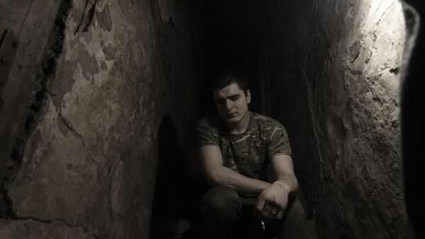 A Ukrainian serviceman smokes in a shelter at a position at the line of separation. - Sputnik भारत