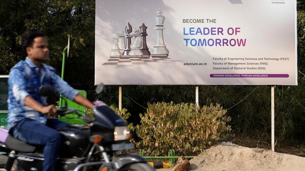 A motorist rides past a hoarding of Adani University near the corporate headquarters of Adani Group in Ahmedabad, India, Friday, Jan. 27, 2023. - Sputnik India