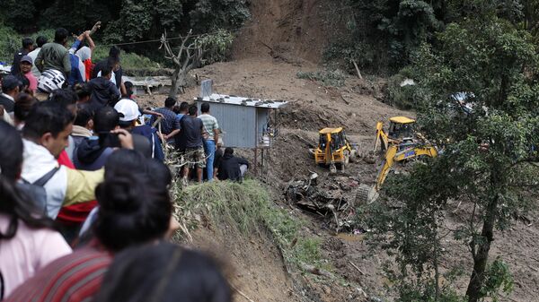 People watch earthmovers removing automobile debris and the dead bodies of victims  trapped under a landslide caused by heavy rains in Kathmandu, Nepal, Sunday, Sept. 29, 2024. - Sputnik India