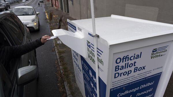 A person drops off their 2024 election ballot at a newly installed drop box outside the Multnomah County Elections Division office on Monday, Oct. 28, 2024, in Portland, Ore.  - Sputnik भारत