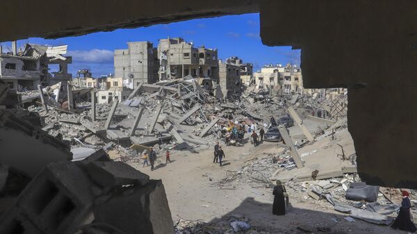 Palestinians walk through the rubble caused by the Israeli air and ground offensive in Rafah, southern Gaza Strip, Monday, Jan. 20, 2025. - Sputnik India