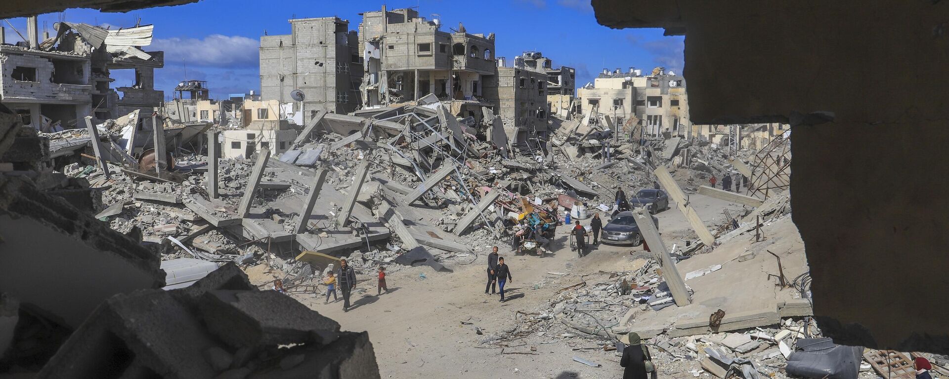 Palestinians walk through the rubble caused by the Israeli air and ground offensive in Rafah, southern Gaza Strip, Monday, Jan. 20, 2025. - Sputnik India, 1920, 02.07.2025