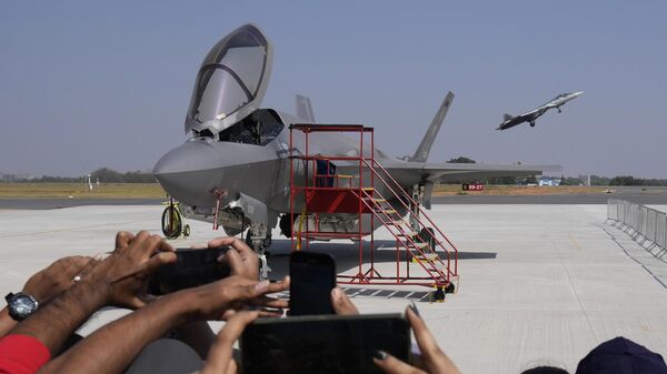 Visitors take pictures as Russia's Su-57 fighter aircraft takes off behind the U.S. Air Force fighter aircraft F-35, parked at the static display area, on the last day of the Aero India 2025, a biennial event, at Yelahanka air base in Bengaluru, India, Friday, Feb. 14, 2025. (AP Photo/Aijaz Rahi) - Sputnik India