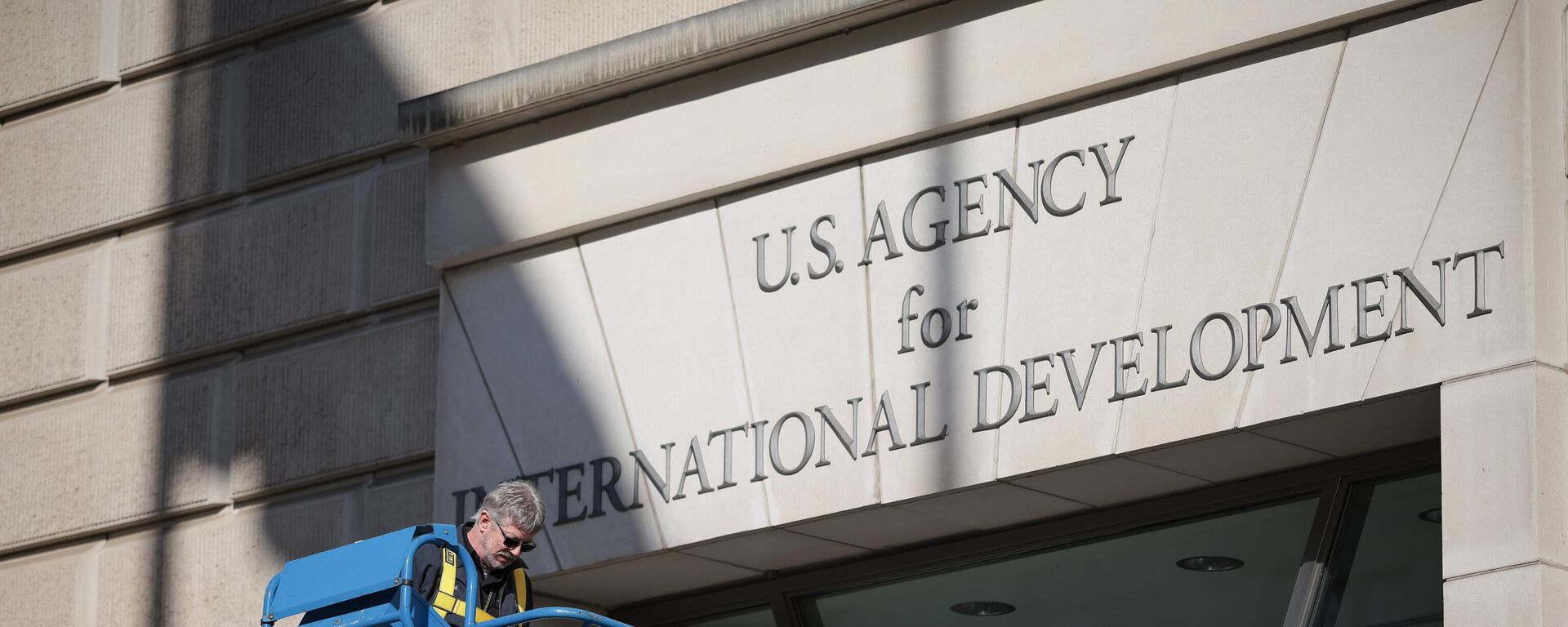 WASHINGTON, DC - FEBRUARY 07: A worker removes the U.S. Agency for International Development sign on their headquarters on February 07, 2025 in Washington, DC. President Donald Trump and Elon Musk's Department of Government Efficiency (DOGE) abruptly shutdown the U.S. aid agency earlier this week leaving thousands unemployed and putting U.S. foreign diplomacy and aid programs in limbo.  (Photo by Kayla Bartkowski/Getty Images) - Sputnik India, 1920, 18.02.2025