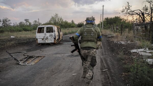 A serviceman of the 24th Mechanised Brigade runs past a damaged car at the frontline in Donetsk region.   - Sputnik भारत