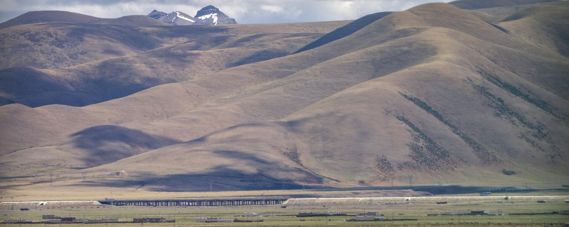 Yaks graze around tents set up for herders to live in the during the summer grazing season on grasslands near Lhasa in western China's Tibet Autonomous Region, as seen during a rare government-led tour of the region for foreign journalists, Wednesday, June 2, 2021. - Sputnik भारत, 1920, 27.03.2025
