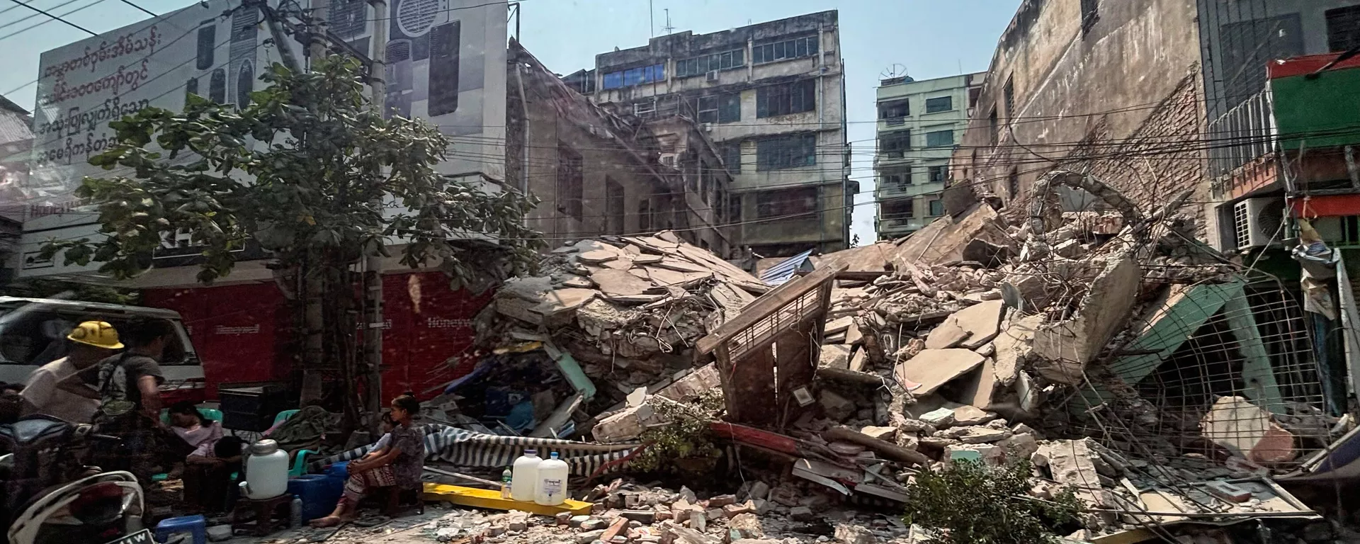 Local residents rest near a damaged building in the aftermath of an earthquake, in Mandalay, central Myanmar, Sunday, March 30, 2025.  - Sputnik भारत, 1920, 02.04.2025