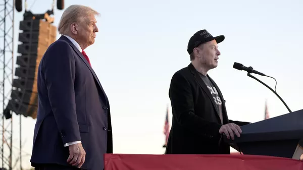 Tesla and SpaceX CEO Elon Musk speaks as Donald Trump listens at a campaign event at the Butler Farm Show, Saturday, Oct. 5, 2024. - Sputnik भारत