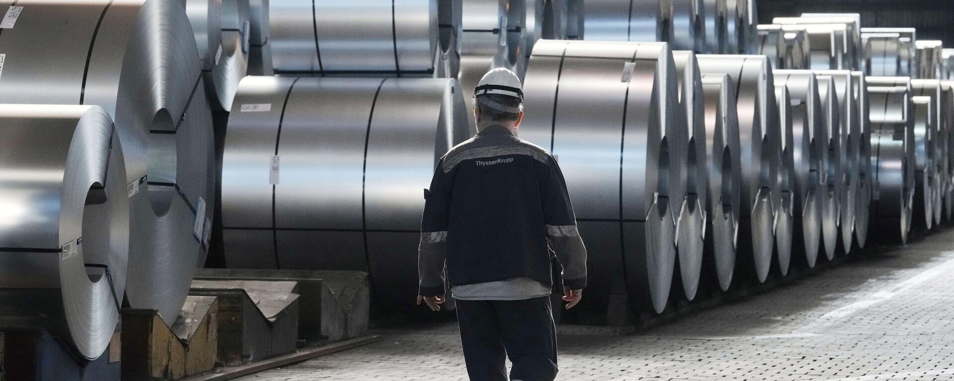 A steel worker walks beside steel coils during a visit of EU Commissioner for Prosperity and Industrial Strategy Stephane Sejourne at the Thyssenkrupp steelworks in Duisburg, Germany, on March 20, 2025.  - Sputnik India, 1920, 31.05.2025