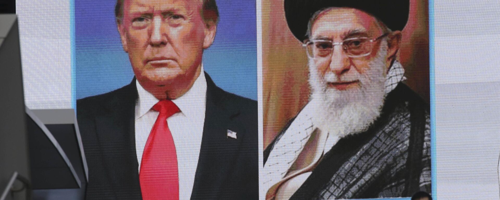 A man walks by a huge screen showing U.S. President Donald Trump, left, and Iranian Supreme Leader Ayatollah Ali Khamenei, in Tokyo, Wednesday, Jan. 8, 2020. Iran struck back at the United States early Wednesday for killing a top Revolutionary Guards commander, firing a series of ballistic missiles at two military bases in Iraq housing American troops in a major escalation between the two longtime foes. (AP Photo/Koji Sasahara) - Sputnik भारत, 1920, 29.06.2025