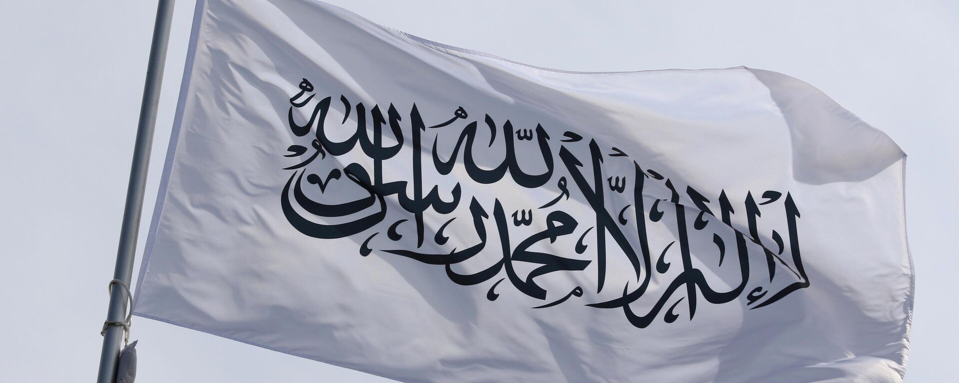 The national flag of the Islamic Emirate of Afghanistan, the Taliban, fluttering in the wind on a flagpole in Saint Petersburg, Russia. - Sputnik भारत, 1920, 04.07.2025