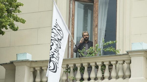 A man talks by a phone while standing on a balcony of the Afghan Embassy in Moscow, Russia, Friday, July 4, 2025, where the flag of the Islamic Emirate of Afghanistan was raised after Russia recognized the Taliban government in Afghanistan. - Sputnik India