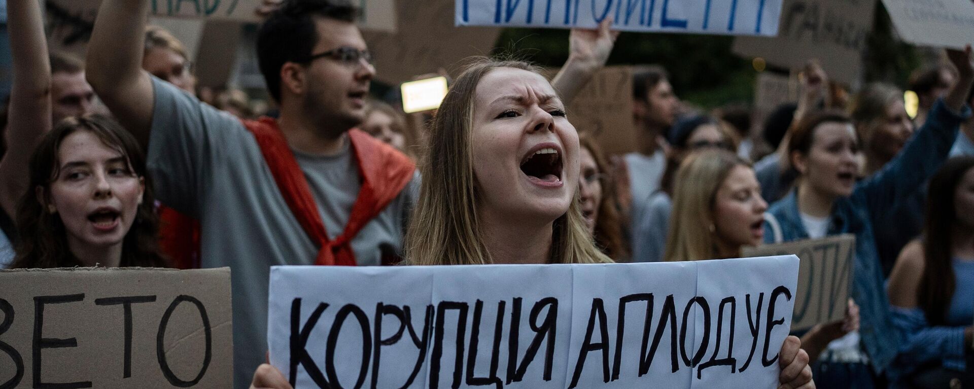 A woman chants while holding a banner that reads, “Corruption Applauds,” during a protest against a law targeting anti-corruption institutions in central Kiev, Ukraine, Tuesday, July 22, 2025 - Sputnik भारत, 1920, 24.07.2025