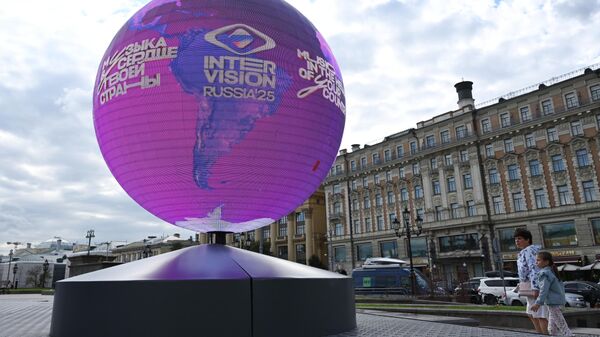 Горожане во время прогулки в Москве. В честь юбилейной даты 50 дней до финала Интервидения на Манежной площади была установлена инсталляция земного шара, на котором изображены страны – участницы конкурса, как символ мирового праздника музыки. - Sputnik भारत