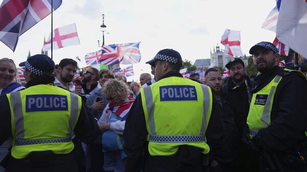 Police officers form a line in front of demonstrators from the Tommy Robinson-led Unite the Kingdom march and rally near Westminster, London, Saturday Sept. 13, 2025.  - Sputnik India