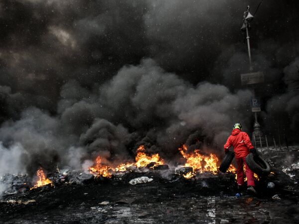 A protester adds tire to the fire in Maidan square in Kiev, Ukraine, Jan 22, 2014  - Sputnik India