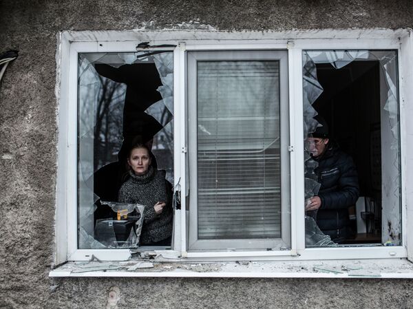 A Ukrainian woman looks through a broken window at their flat after it was hit by Ukrainian Artillery in the Voroshilovsky area, center of Donetsk, Ukraine. Sunday, Jan. 18, 2015 - Sputnik भारत
