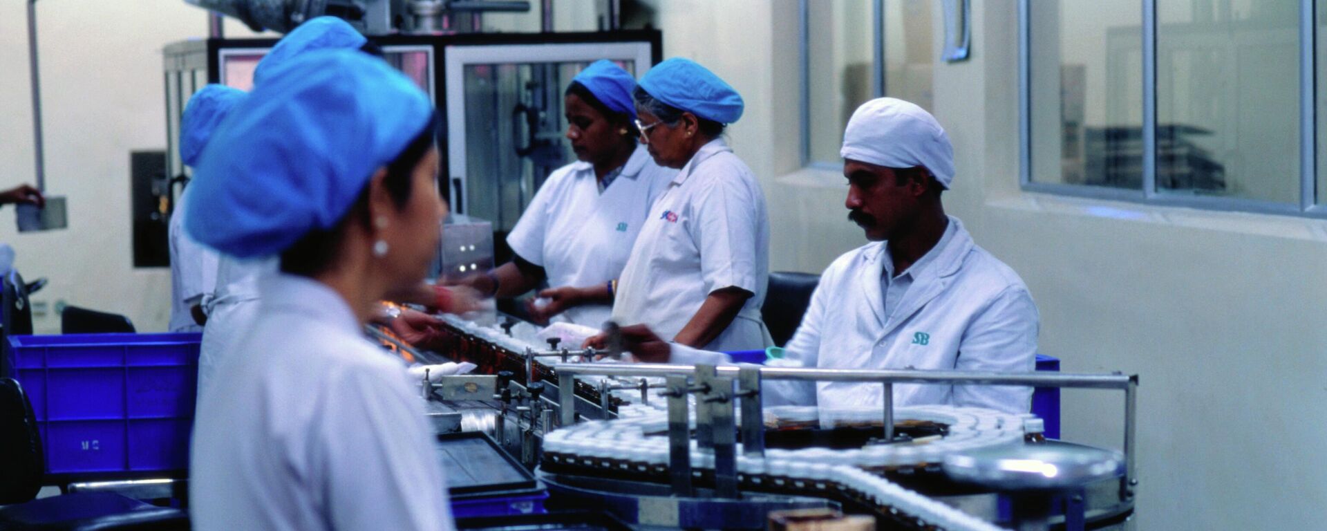 Workers watch drugs flow through the assembly line of the SmithKline Beecham pharmaceutical factory in Bangladore, India. - Sputnik भारत, 1920, 17.11.2025