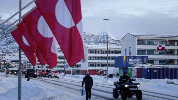 A man rides by on a quad bike past a row of Greenlandic national flags in Nuuk, Greenland, Wednesday, Jan. 14, 2026. - Sputnik भारत