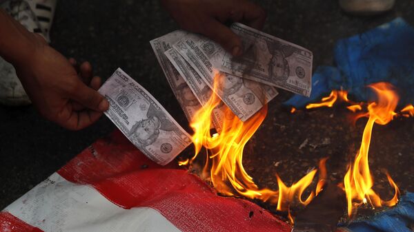 A supporter of a communist group burns representation of U.S. currency, during a protest against U.S. interference in Lebanon's affairs, near the U.S. embassy, in Aukar northeast of Beirut, Lebanon, Friday, July 10, 2020 - Sputnik भारत