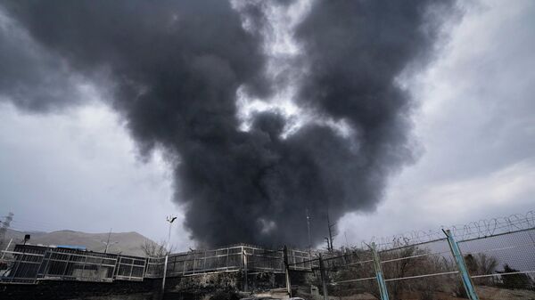 A thick plume of smoke rises from an oil storage facility hit by a U.S.-Israeli strike late Saturday in Tehran, Iran, March 8, 2026.  - Sputnik India
