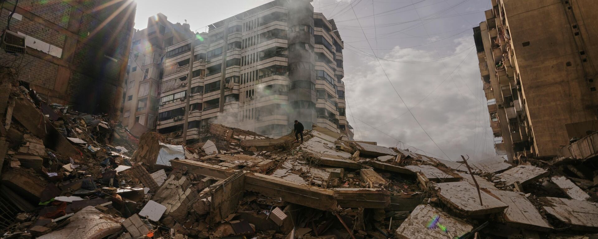 A man stands atop the rubble as smoke rises from a building destroyed in an Israeli airstrike in Dahiyeh, Beirut's southern suburbs, Lebanon, Saturday, March 14, 2026. (AP Photo/Hassan Ammar) - Sputnik भारत, 1920, 26.03.2026