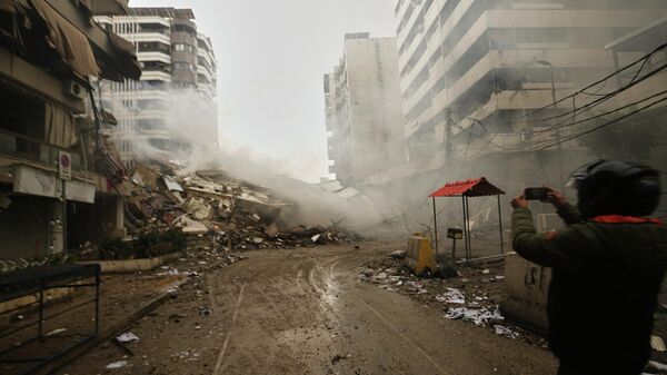 A man photographs the rubble of buildings destroyed in an Israeli airstrike in Dahiyeh, Beirut's southern suburbs, Lebanon, Sunday, March 15, 2026. (AP Photo/Hassan Ammar) - Sputnik भारत
