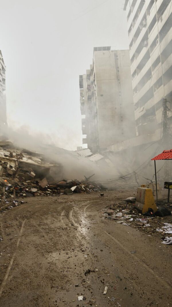 A man photographs the rubble of buildings destroyed in an Israeli airstrike in Dahiyeh, Beirut's southern suburbs, Lebanon, Sunday, March 15, 2026. (AP Photo/Hassan Ammar) - Sputnik भारत