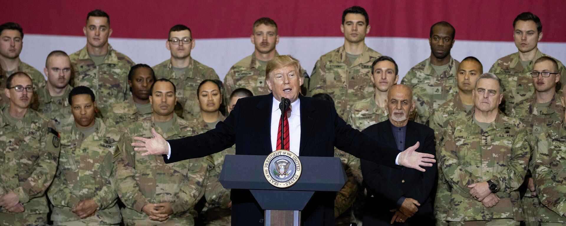 President Donald Trump, center, with Afghan President Ashraf Ghani and Joint Chiefs Chairman Gen. Mark Milley, behind him at right, while addressing members of the military during a surprise Thanksgiving Day visit, Thursday, Nov. 28, 2019, at Bagram Air Field, Afghanistan - Sputnik भारत, 1920, 01.04.2026