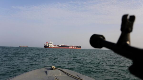 In this Sunday, July 21, 2019 photo, a speedboat of Iran's Revolutionary Guard trains a weapon toward the British-flagged oil tanker Stena Impero, which was seized in the Strait of Hormuz on Friday by the Guard, in the Iranian port of Bandar Abbas. Global stock markets were subdued Monday while the price of oil climbed as tensions in the Persian Gulf escalated after Iran's seizure of a British oil tanker on Friday.  - Sputnik India