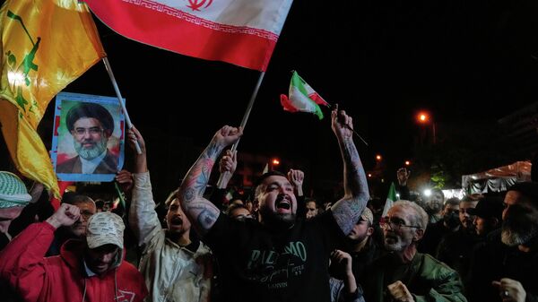 Iranians chant slogans as they hold Iranian flags and a poster of the Supreme Leader Ayatollah Mojtaba Khamenei in a gathering after announcement of a two-week ceasefire in the war with the United States and Israel, at the Enqelab-e-Eslami, or Islamic Revolution, Square, in Tehran, Iran, Wednesday, April 8, 2026.  - Sputnik भारत