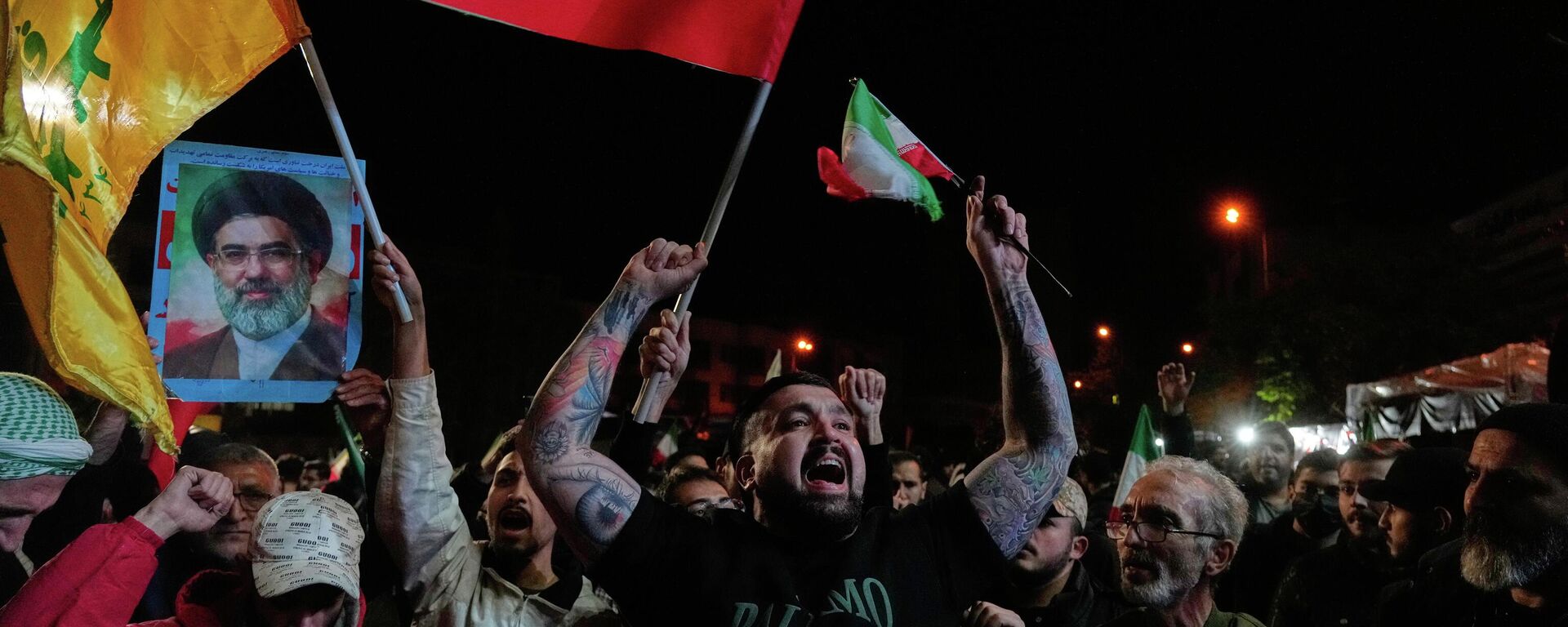 Iranians chant slogans as they hold Iranian flags and a poster of the Supreme Leader Ayatollah Mojtaba Khamenei in a gathering after announcement of a two-week ceasefire in the war with the United States and Israel, at the Enqelab-e-Eslami, or Islamic Revolution, Square, in Tehran, Iran, Wednesday, April 8, 2026.  - Sputnik भारत, 1920, 10.04.2026