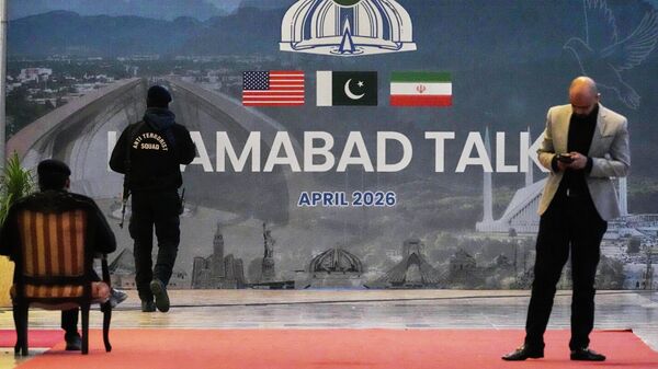 A security guard walks past a billboard  of the U.S. Iran talks outside a media center set up for the coverage of the U.S. Iran official meeting, in Islamabad, Pakistan, April 12, 2026.  - Sputnik भारत