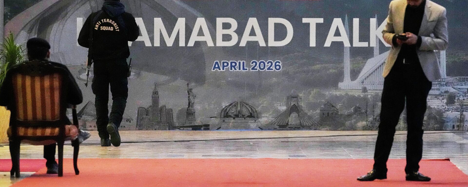 A security guard walks past a billboard  of the U.S. Iran talks outside a media center set up for the coverage of the U.S. Iran official meeting, in Islamabad, Pakistan, April 12, 2026.  - Sputnik भारत, 1920, 18.04.2026