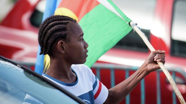 An Independence supporter holds the Kanak flag outside a voting station in the Riviere Salee district of Noumea, New Caledonia, Oct.4, 2020. - Sputnik भारत