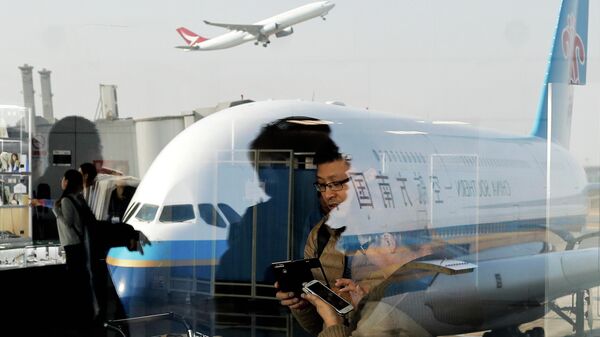 FILE - Passengers walk past a couple browsing their smartphones near a China Southern Airlines, parked on the tarmac at the Beijing Capital International Airport Saturday, Nov. 19, 2016.(AP Photo/Andy Wong, File) - Sputnik India