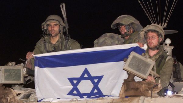 Israeli soldiers ride atop their armored vehicle holding an Israeli flag as they withdraw from south Lebanon into Israel, at the Israeli-Lebanese border near Metulla, early Wednesday, May 24, 2000.  - Sputnik भारत