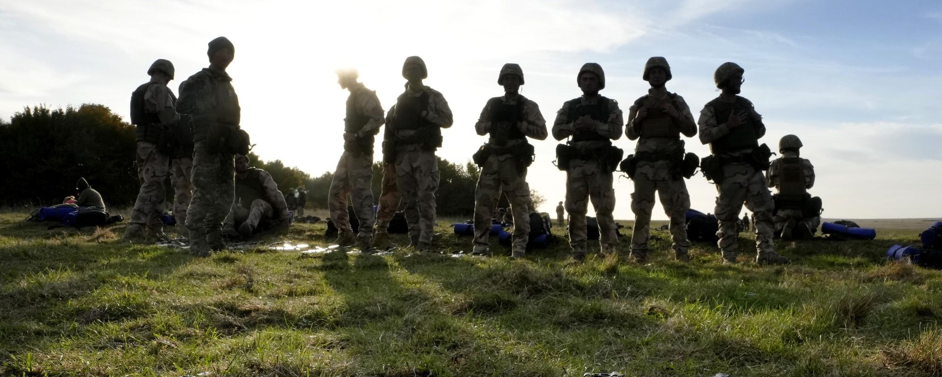 Weapons lie on the ground as Ukrainian personnel take a break during training  - Sputnik India, 1920, 30.06.2026