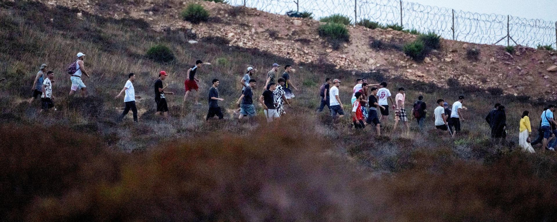 People walk past barbed wire in a forest in the northern Moroccan town of Fnideq as they attempt to cross to the Spanish enclave of Ceuta, Thursday, July 30, 2026. People walk past barbed wire in a forest in the northern Moroccan town of Fnideq as they attempt to cross to the Spanish enclave of Ceuta, Thursday, July 30, 2026. - Sputnik India, 1920, 31.07.2026