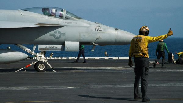 A crew member signals as a pilot prepares to launch an F/A-18 fighter jet on the deck of the USS Abraham Lincoln aircraft carrier in the Arabian Sea. File photo. - Sputnik India