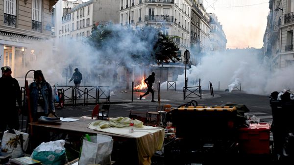 A protester runs through tear gas while a flea market is taking place during clashes between protestors and police officers in Paris, Sunday, Oct. 18, 2026.  - Sputnik भारत